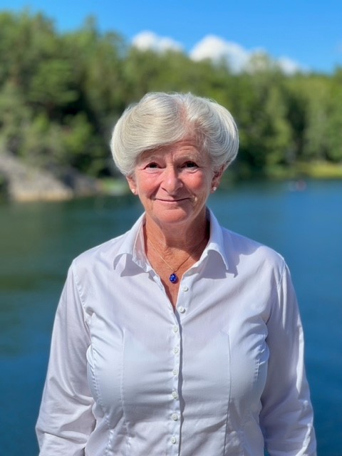 Portrait of Monica Schüldt with the ocean and trees in the background.